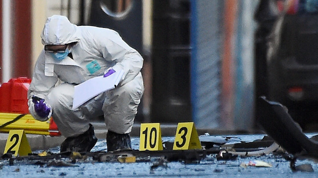 A forensic officer inspects the scene of a suspected car bomb in Londonderry,