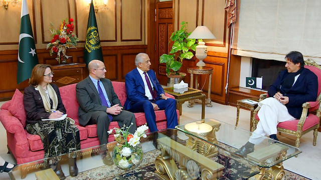 Pakistani Prime Minister Imran Khan (R) speaks with U.S. special envoy Zalmay Khalilzad 