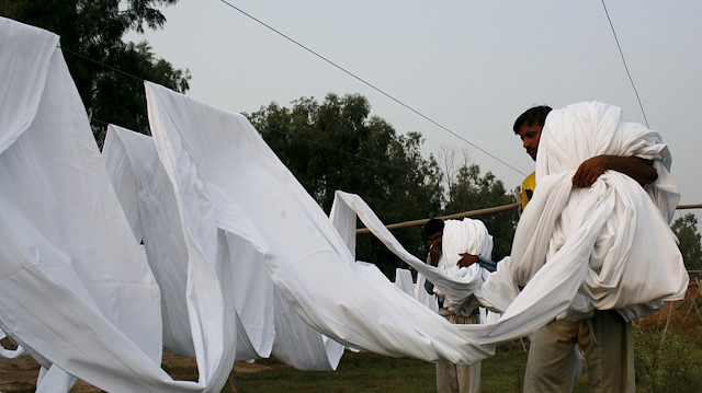 Workmen collect dried cloth used to make undershirts at a garment factory in Faisalabad, Pakistan October 12, 2015. REUTERS/Fayyaz Hussain