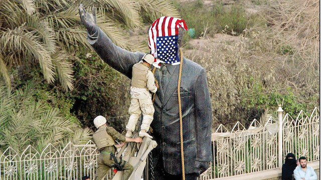 Saddam Hüseyin heykelinin devirilmesi öncesi ABD askerleri heykele halat geçirirken.