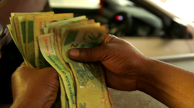 A petrol attendant counts bond notes at a filling station in Harare, Zimbabwe