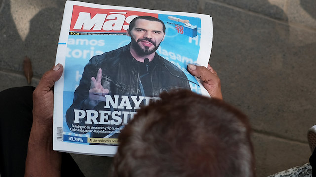 A man reads a newspaper with the picture of presidential candidate Nayib Bukele
