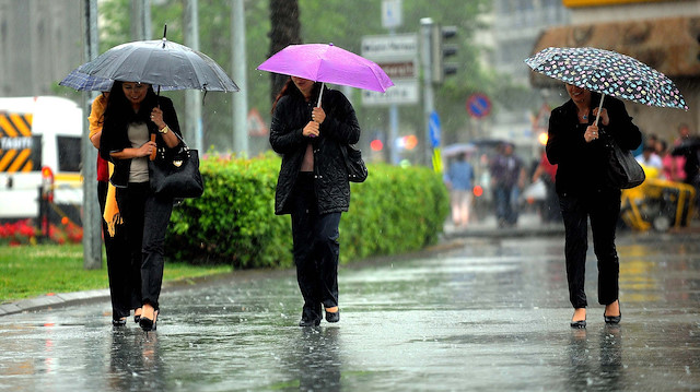 Yağmurdan şemsiyeyle korunmaya çalışan vatandaşlar.