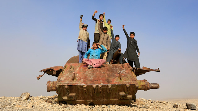 Afghan children play on the remains of a Soviet-era tank on the outskirts of Jalalabad, Afghanistan February 15, 