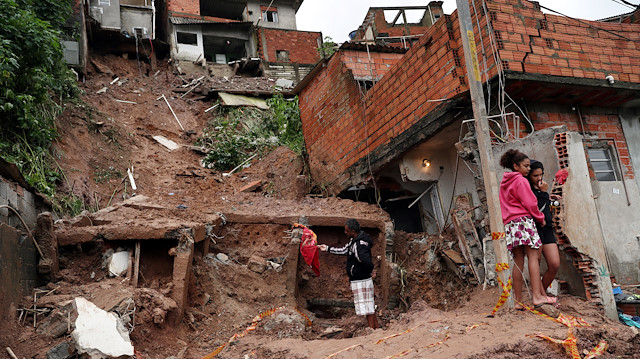 Residents look at a house damaged in a mudslide after heavy rains in Maua, Brazil 

