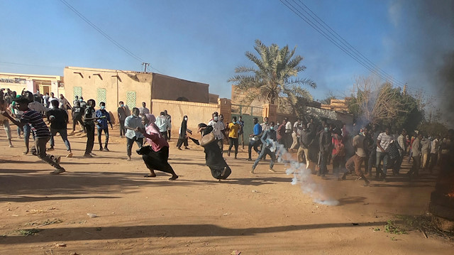 Sudanese demonstrators run from a teargas canister fired by riot policemen to disperse them as they participate in anti-government protests in Omdurman, Khartoum, Sudan.