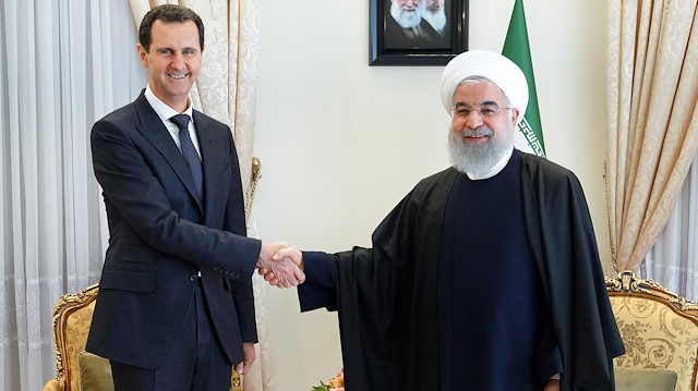 Syria's President Bashar al-Assad shakes hands with Iranian President Hassan Rouhani
