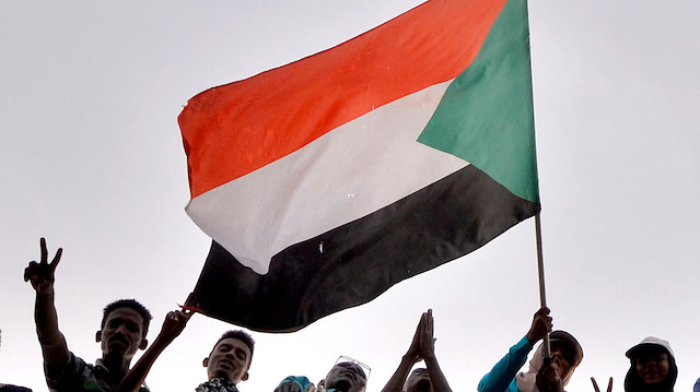 Sudanese demonstrators wave their national flag as they attend a protest rally