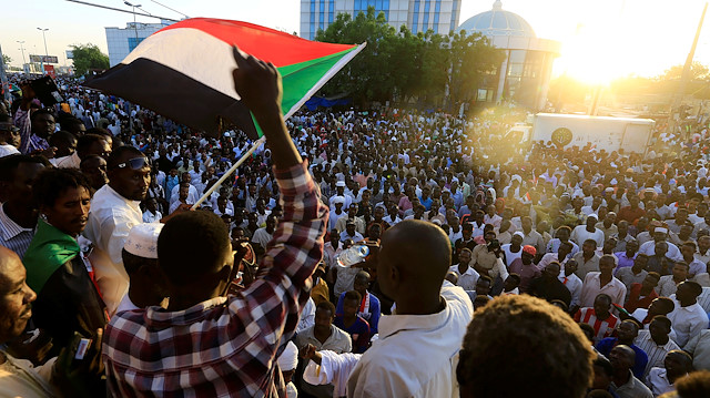 File photo: Sudanese demonstrators wave their national flags 