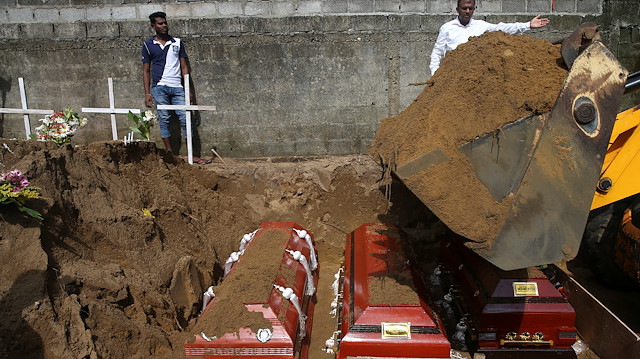 Men coordinate a mass burial of victims, two days after a string of suicide bomb attacks