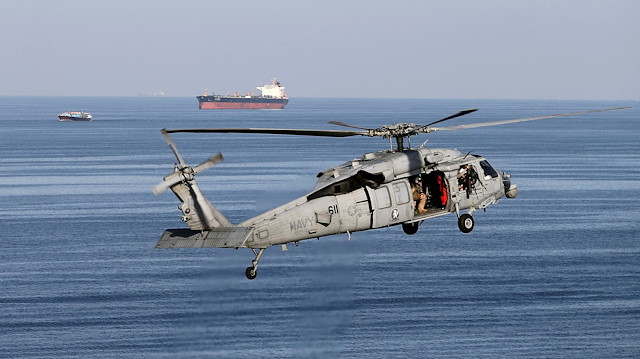 File photo: MH-60S helicopter hovers in the air with an oil tanker in the background as the USS John C. Stennis makes its way to the Gulf through the Strait of Hormuz
