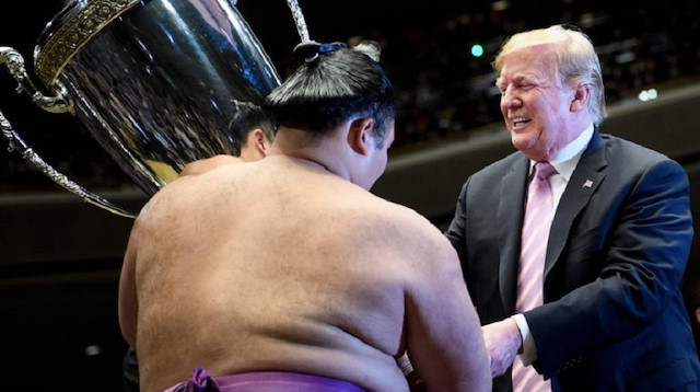 Donald Trump presents the President's Cup to a sumo wrestler during the Summer Grand Sumo Tournament 