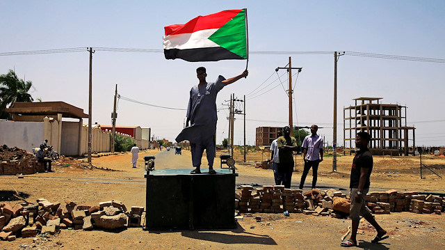 A Sudanese protester holds a national flag as he stands on a barricade along a street, demanding that the country's Transitional Military Council hand over power to civilians, in Khartoum, Sudan June 5, 2019. REUTERS/Stringer

