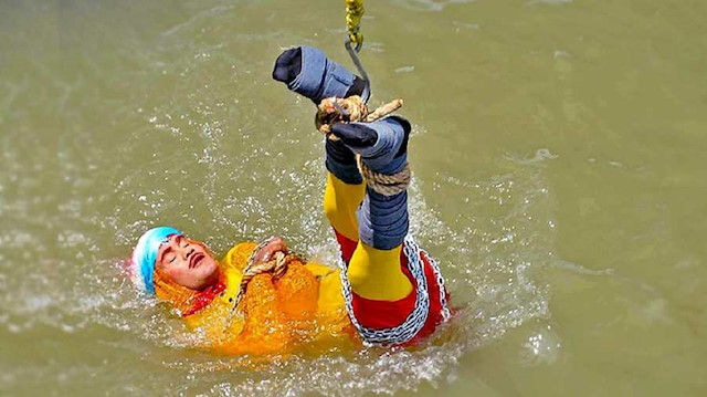 Chanchal Lahiri lowered into the Ganges river, while tied up with steel chains and ropes