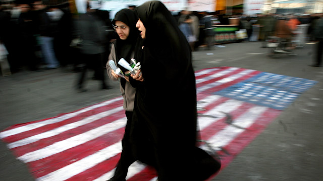 : Iranian women walk on a U.S. flag during a demonstration 