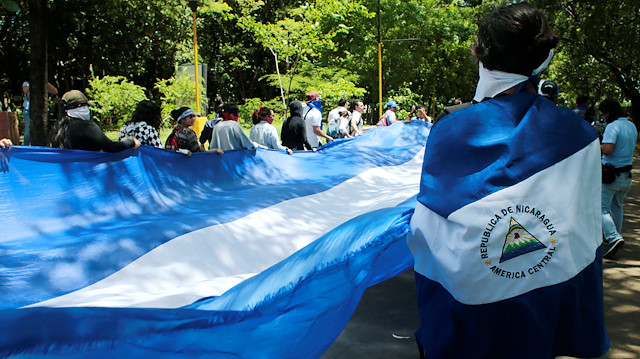 Demonstrators hold a big national flag during a protest against Nicaraguan President 