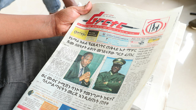 An Ethiopian man reads a newspaper with the pictures of Amhara state President 