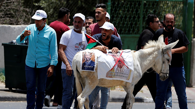 Palestinian demonstrators hang on a donkey a crossed-out poster depicting Bahrain's King 