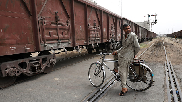 A man on a bicycle waits to cross a passageway as cargo train passes in Karachi, Pakistan September 16, 2018. Picture taken September 16, 2018. REUTERS/Akhtar Soomro  