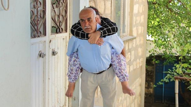 63 yaşındaki Abdullah ​Örün​​, hasta kızını sırtında taşıyor. 