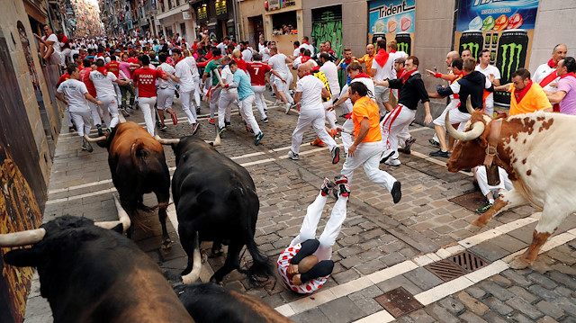 A runner falls near bulls and steers during the running of the bulls at the San Fermin festival in Pamplona, Spain, July 13, 2019.
