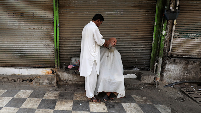 A shopkeeper gets shave from a street barber in front of closed shops during a shutter down strike called by the traders and business community against, what they say is harsh federal budget for the fiscal year 2019-20, and imposition of taxes by the Federal Board of Revenue (FBR) in Peshawar, Pakistan