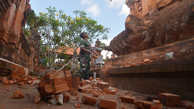 An Indonesian soldier looks at a Hindu temple damaged following an earthquake in Denpasar, Bali, Indonesia, July 16, 2019 in this photo taken by Antara Foto