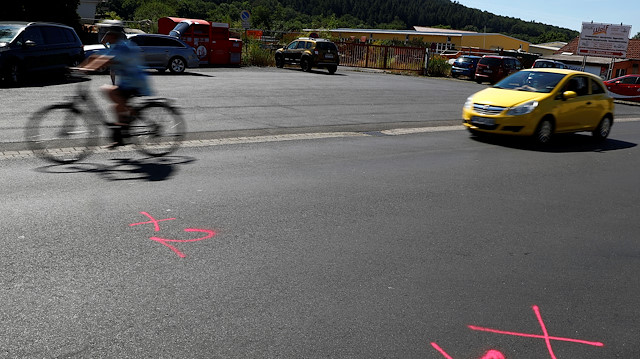 A car passes the marks left by police forensic experts on a street where shots were fired