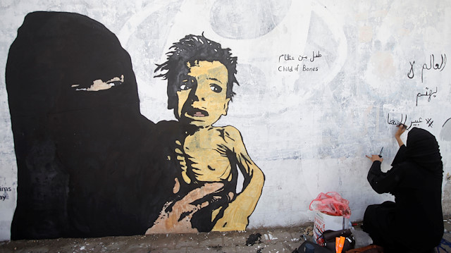 File photo: A friend of artist Haifa Subay writes on a mural about children and women suffering in the time of war in Sanaa, Yemen February 21, 2019. Picture taken February 21, 2019