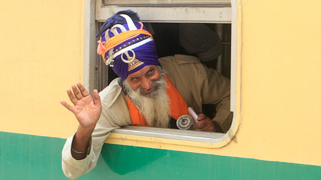 Indian Sikh pilgrim waves from a window of a train as he arrives at the Wagah border railway station 