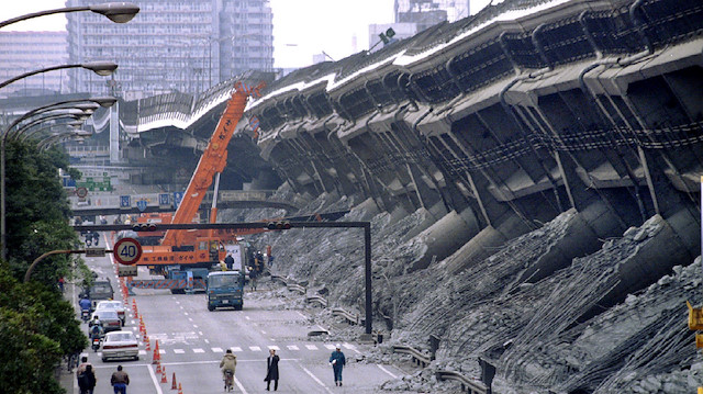 FILE PHOTO: A giant crane pulls crushed cars out of the debris January 18, 1995, after the Hanshin Expressway was devastated during the worst earthquake in Japan in nearly 50 years in Kobe, Japan. REUTERS/Kimimasa Mayama/File Photo

