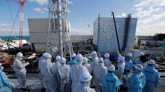 FILE PHOTO: Members of the media, wearing protective suits and masks, receive briefing from Tokyo Electric Power Co. (TEPCO) employees (in blue) in front of the No. 1 (L) and No.2 reactor buildings at TEPCO's tsunami-crippled Fukushima Daiichi nuclear power plant in Okuma town, Fukushima prefecture, Japan February 10, 2016. REUTERS/Toru Hanai/File Photo

