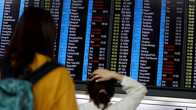 Passengers react as they look at the flight information board as the airport reopened