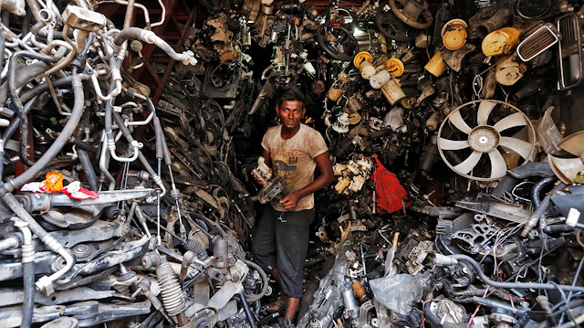 A worker carries a part of a used car inside a shop at a second-hand automobile parts market in Mumbai, India June 1, 2016. 