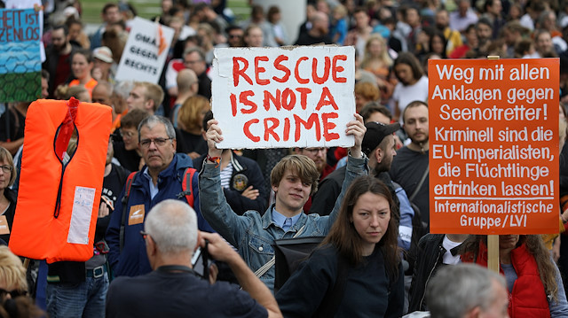 A man holding a sign that reads "Rescue is not a Crime", attends a demonstration 