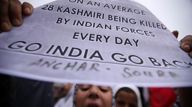 A Kashmiri girl displays a placard as she shouts slogans at a protest after Friday prayers 