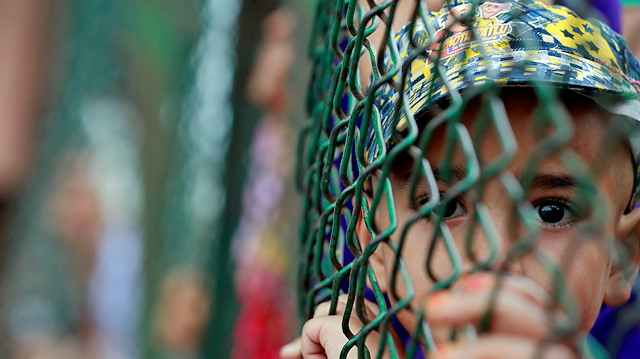 Kashmiri child looks from behind a fence at a protest site after Friday prayers