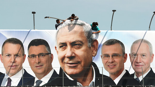 FILE PHOTO: Labourers work on hanging up a Likud election campaign banner depicting Israeli Prime Minister Benjamin Netanyahu with his party candidates, in Jerusalem March 28, 2019. REUTERS/Ammar Awad/File Photo

