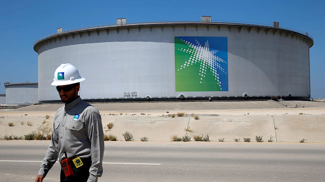 File photo: An Aramco employee walks near an oil tank at Saudi Aramco's Ras Tanura oil refinery