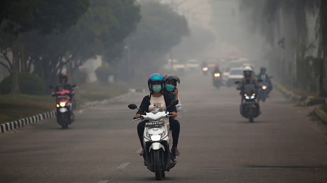 Motorists ride their motorbikes through haze due to a forest fire in Palangka Raya, Central Kalimantan province, Indonesia, September 15, 2019.