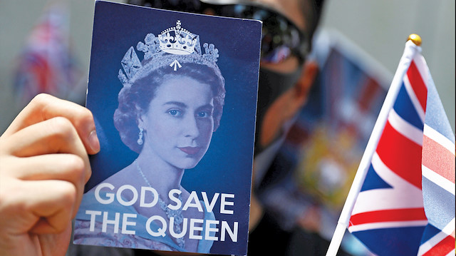 Çin karşıtı göstericiler dün İngiliz kraliçesi için “Tanrı Kraliçe’yi korusun” pankartı taşıdı.