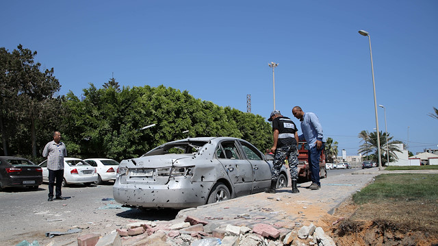 A Libyan police checks a damaged civilian vehicle