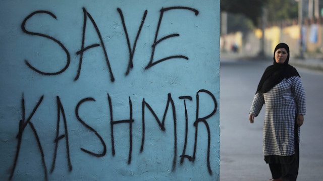 File photo: A Kashmiri woman stands next to a graffiti written on a wall during restrictions, following scrapping of the special constitutional status for Kashmir by the Indian government, in Srinagar 
