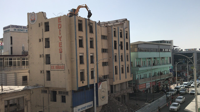 Şanlıurfa'da yıkım için 7 katlı binanın çatısına çıkarılan iş makinesi dikkat çekti.
