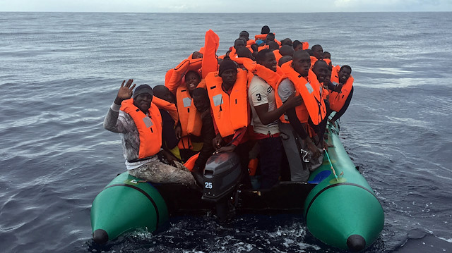Migrants wave from a rubber boat as they are rescued by members of the NGO Proactiva 