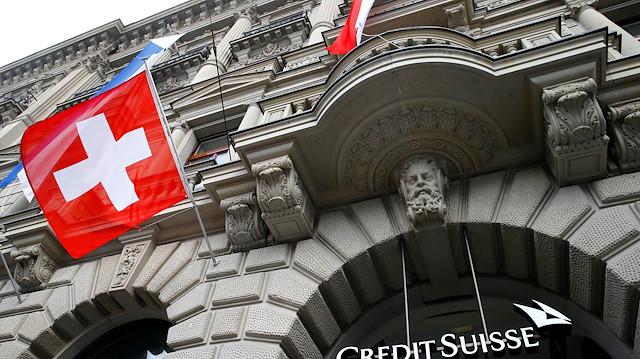 FILE PHOTO: Switzerland's national flag flies below a logo of Swiss bank Credit Suisse
