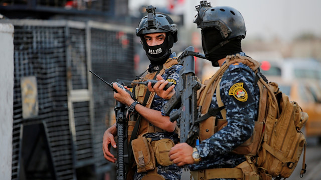 Irak federal polisinin üyeleri, Bağdat'ta bir sokakta askeri araçlarla görülüyor. 