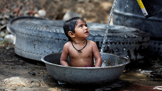 FILE PHOTO: A baby girl cools off as her mother (not pictured) fills the tub with water on a hot summer day, outside a farm on the outskirts of Ahmedabad, India May 2, 2017. REUTERS/Amit Dave/File Photo

