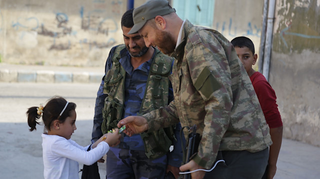 File photo: A Syrian National Army member gives candies to childen