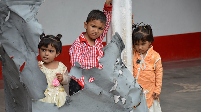 File photo: Children hold a piece of the roof of their house, damaged during recent clashes between Pakistan and India, in Tarkundi village, Nikyal Sector in Pakistan-Administered Kashmir 